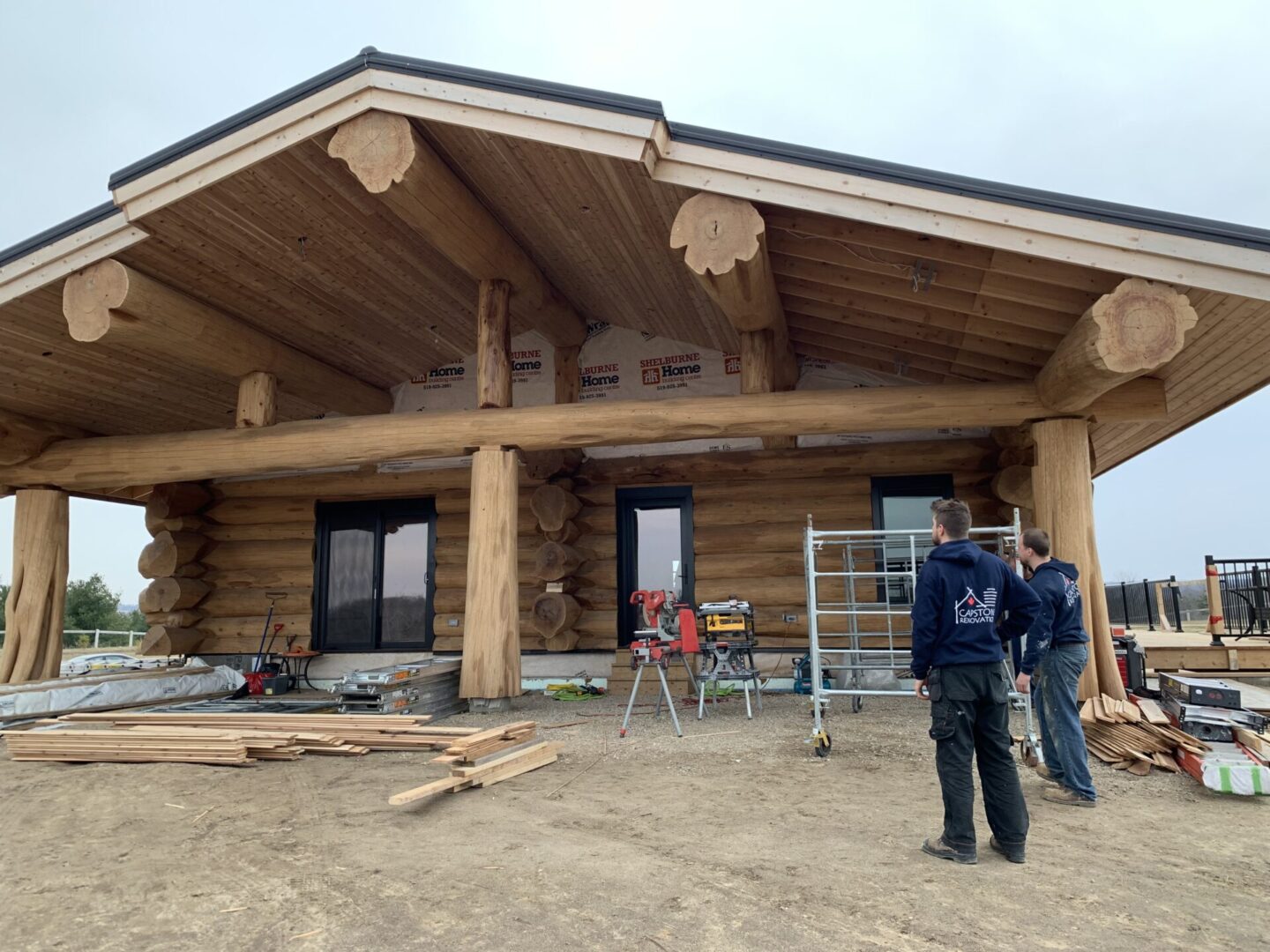 Two men standing in front of a log house.